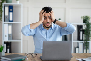 Homem assustado diante do computador ao ver seus 7 principais erros de empreendedor iniciante